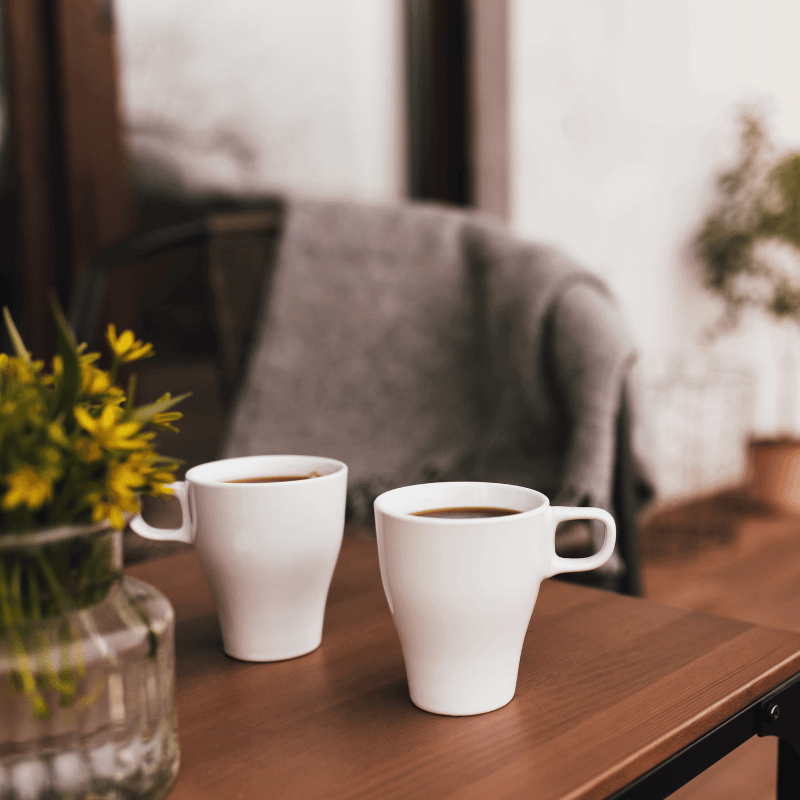 Two cups of coffee on a wooden table.